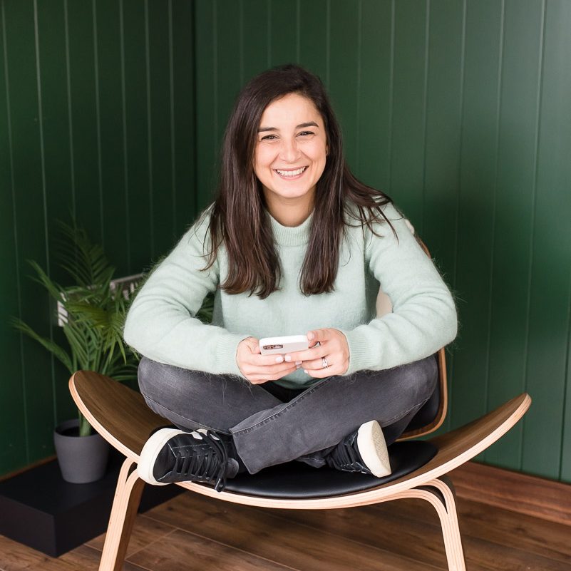 brand sitting on chair cross legged with phone